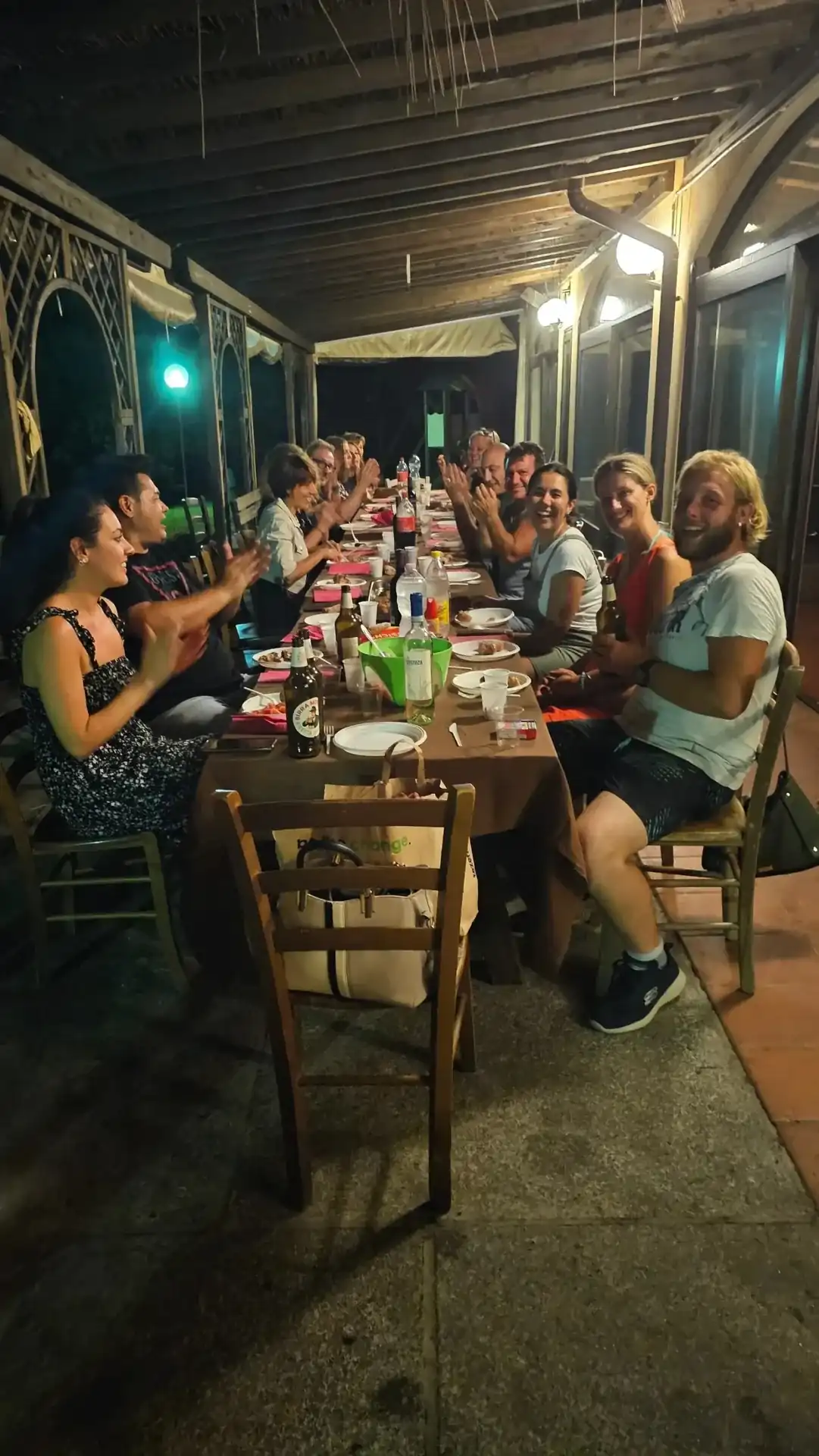 Soci del circolo a tavola sotto il portico durante una cena serale al maneggio