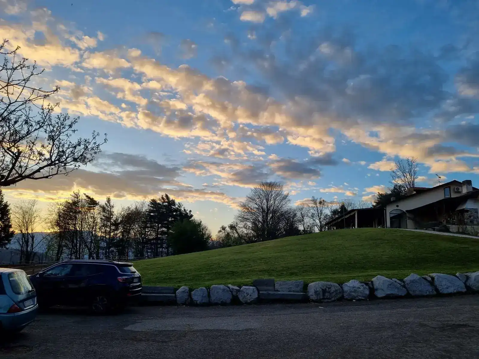 Tramonto sul maneggio Mitena Ranch con il prato in collina e la struttura sullo sfondo