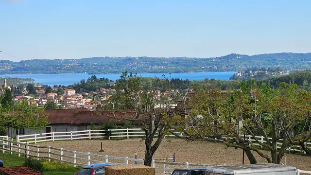 Campo in sabbia con staccionata bianca e vista panoramica sul lago e sulle colline