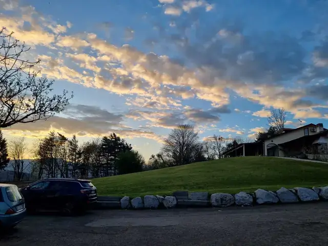 Tramonto sul maneggio Mitena Ranch con il prato in collina e la struttura sullo sfondo