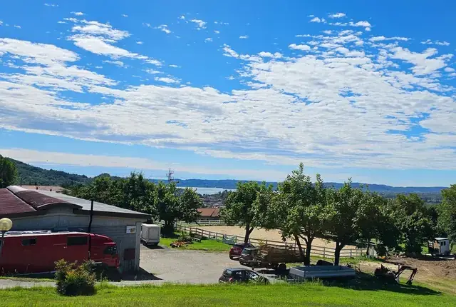 Panorama del maneggio con paddock, camion cavalli e il lago all'orizzonte sotto il cielo azzurro